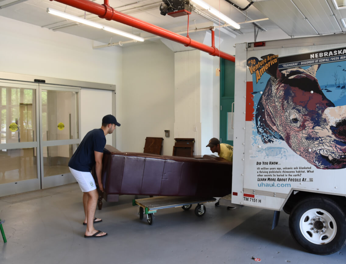 2 men lifting a sofa from a moving truck